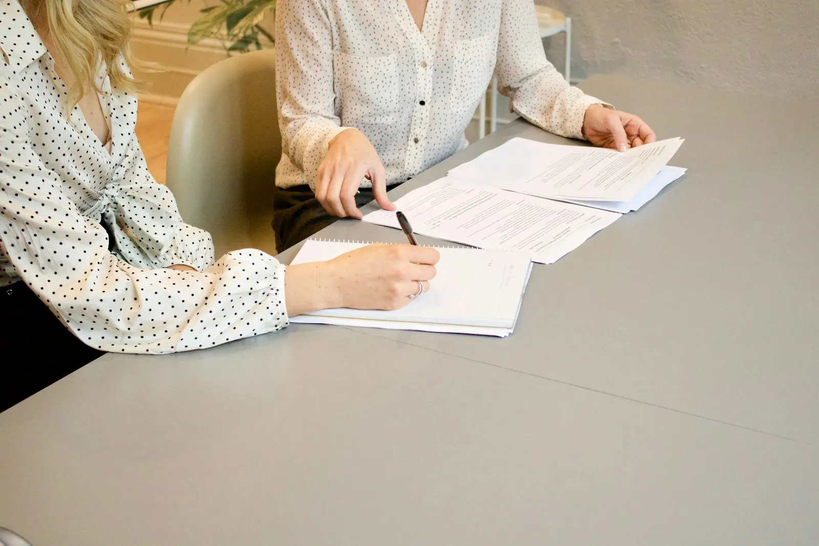 Two professionals reviewing and signing documents across a desk during a consultation